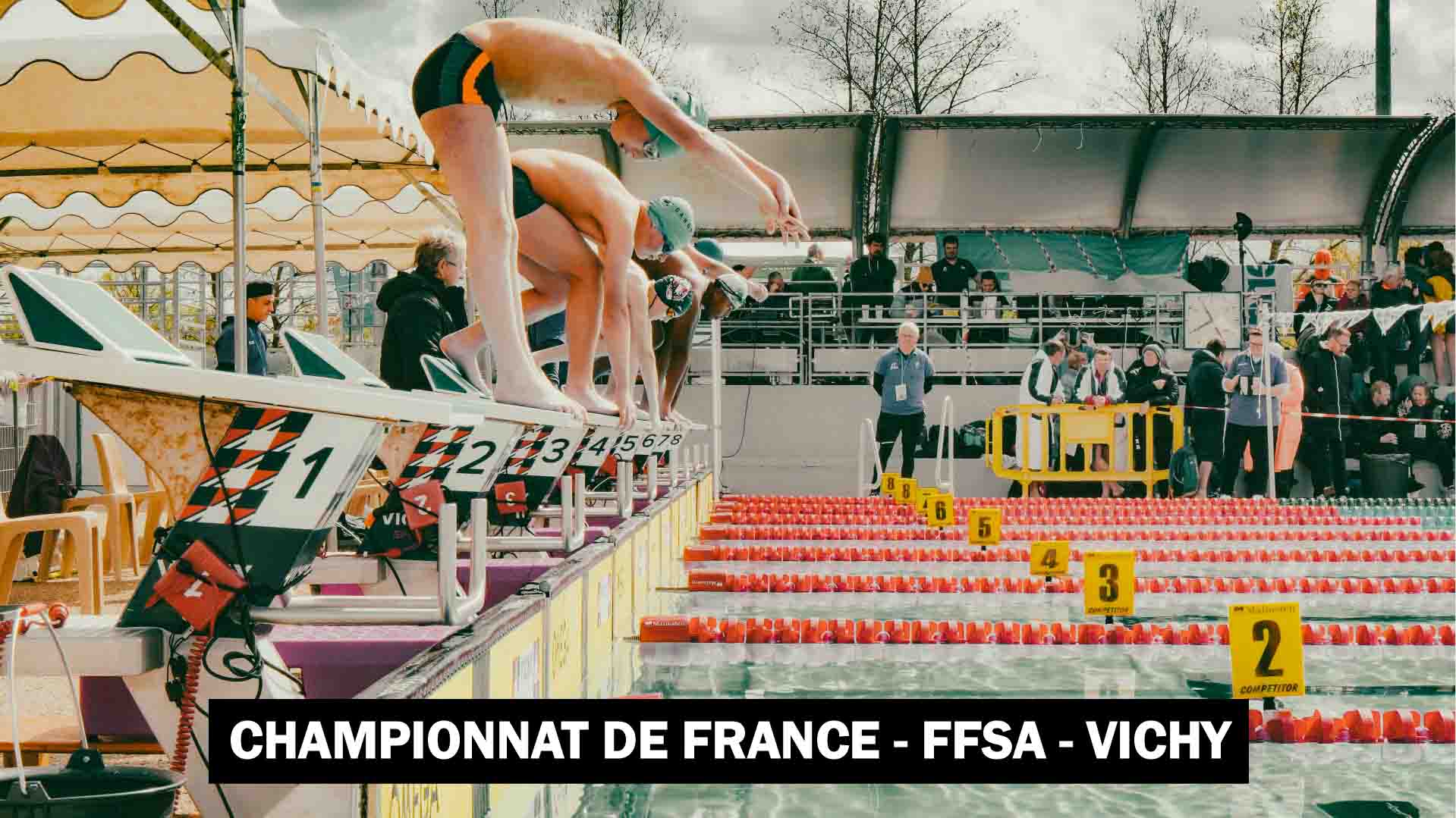 Des plongeurs s'apprêtent à sauter dans le bassin pour une course de natation.