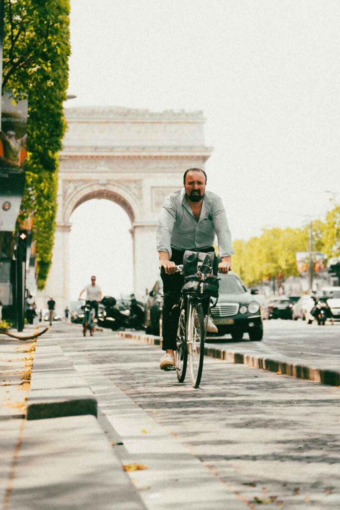 L'Arc de triomphe vu des Champs-Élysées avec un cycliste.